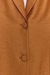 Blazer entallado color tostado confeccionado con lino. Cuenta con cuello solapa, manga larga con hombreras y cierre frontal con dos botones forrados a tono. Presenta forrería interior blanca.