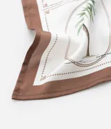 Pañuelo de poliéster satinado, color crema, con estampa botánica en tonos verdes y marrones, y bordes en color marrón oscuro.