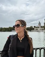 Collar con dije de forma irregular en tonos dorados y plateados, suspendido de un cordón doble de algodón negro.