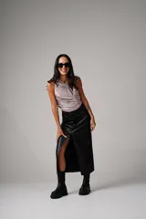Falda midi negra de ecocuero, tiro alto, con bolsillos delanteros y traseros, abertura frontal, cierre con cremallera, botón y presillas para cinturón.
