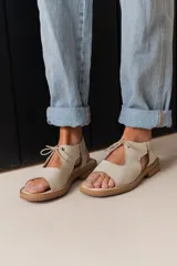 Sandalias de cuero color crudo, con tiras anchas sobre el empeine y ajuste con cordones finos.