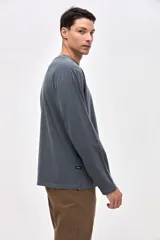 Remera manga larga de algodón lavado con textura suave, color gris oscuro, con estampado pequeño en el pecho y estampado en la manga.