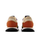 Championes New Balance modelo MS237VE, con capellada de nylon color crema, superposiciones de gamuza en azul marino, verde, amarillo, naranja y bordó. Logo "N" en verde y suela de goma color caramelo.