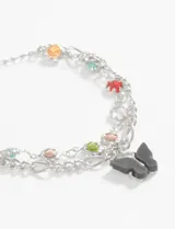 Pulsera plateada de doble cadena con dije de mariposa negra y apliques de strass de colores.