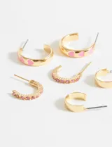 Set de tres pares de aros dorados tipo argolla de diferentes tamaños, uno con detalle de corazones rosados.