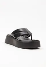 Sandalia tipo ojota con plataforma, confeccionada en material sintético color blanco. Presenta una tira ancha acolchada con detalle de costura central y diseño de separación para el dedo.