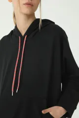 Buzo hoodie negro oversize de rústico, con capucha y cordones de ajuste color salmón y verde. Etiqueta con logo Basset 00'S en la manga derecha.