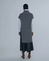 Chaleco largo de punto trenzado color gris con cuello alto y cierre frontal con cremallera metálica.