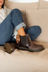 Botas Chelsea de cuero marrón con paneles elásticos laterales y textura símil cocodrilo en la parte trasera, con costura amarilla en la suela gruesa.