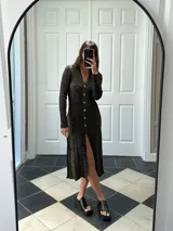 Vestido midi de punto color negro con detalles dorados, escote en V, mangas largas y abertura frontal.