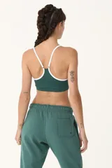 Top deportivo verde con breteles blancos y logo de la marca en el frente.