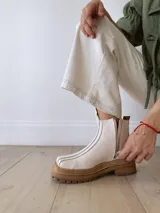 Botas Chelsea de cuero color crudo con elástico lateral, suela track color caramelo y tirador trasero de cuero con textura croco color marrón.