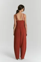 Entero color terracota con escote en V profundo y breteles anchos. La parte superior es ajustada y la parte inferior es un pantalón ancho con pliegues en la cintura.
