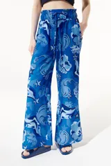 Pantalón fluido de corte flare con pretina elástica, estampado con flores, estrellas y otros motivos en tonos azules.