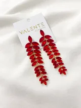Aros colgantes largos con forma de hojas, con cristales rojos engarzados en metal dorado.