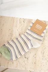 Medias color crudo con rayas horizontales en azul y lila, talón y puntera en verde.