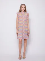 Vestido corto con estampado floral multicolor, cuello tipo camisa y cierre frontal con botones. Presenta volados en las sisas y un diseño de falda con volados en el ruedo.