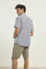 Camisa de manga corta con estampado de rayas verticales en azul y blanco, cuello abotonado y bolsillo frontal en el pecho.