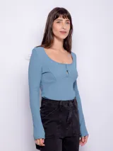 Top de manga larga ceñido al cuerpo, color negro, con escote bote pronunciado y detalle de botones forrados en el centro del pecho.