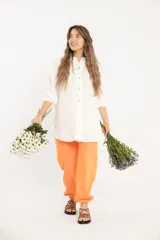 Camisa blanca amplia de manga larga con ruedo curvo.