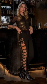 Pantalón negro entallado con aberturas laterales adornadas con hebillas plateadas.