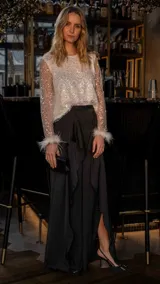 Pantalón palazzo negro con volados frontales y abertura lateral.