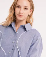 Camisa celeste de algodón con corte oversized, botones frontales a tono y vivos blancos ondulados en el frente.