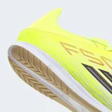 Championes de fútbol sala Adidas F50 Club IN, diseñados para velocidad y precisión. Presentan un exterior de material sintético y malla técnica en color amarillo neón con detalles en blanco y negro, incluyendo las icónicas tres tiras de la marca. Cuentan con lengüeta flotante transpirable y suela de caucho de alta tracción que no deja marcas, ideal para superficies interiores.