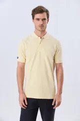 Remera polo piqué de algodón color amarillo, con cuello y puños acanalados, y cierre frontal de botones.