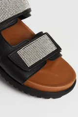 Sandalias planas negras de cuero vacuno con doble tira con apliques de strass y ajuste con velcro.