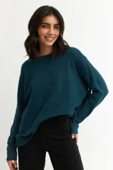 Sweater azul petróleo de tejido de punto, con cuello redondo y botones decorativos en los laterales.