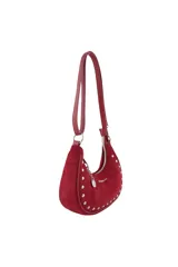 Cartera tipo bandolera de diseño semicircular, confeccionada en material con textura gamuzada color bordó. Presenta detalles de tachas metálicas plateadas en todo el contorno, cierre superior con tirador decorado con un dije metálico circular y correa larga ajustable.