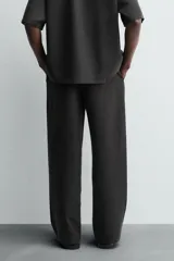 Pantalón de corte relajado confeccionado en tejido fluido con mezcla de lyocell. Presenta cintura elástica ajustable con cordón, bolsillos laterales y un bolsillo trasero de vivo con botón.