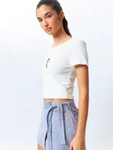 Remera de manga corta color verde lima, ajustada al cuerpo, con un corte cruzado en la parte inferior y un recorte en forma de corazón en el centro del pecho.