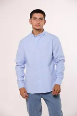 Camisa de manga larga en color gris, confeccionada en algodón, con cuello abotonado y cierre frontal de botones.