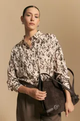 Camisa de manga larga con diseño de rayas verticales en tonos grises y blancos, cuello camisero y cierre frontal con botones.