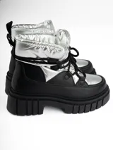 Borcego de caña media color negro con detalles plateados, cordones negros y suela track.