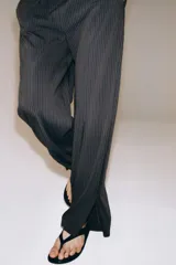 Pantalón de tiro medio con diseño de pierna ancha y estampado de rayas verticales. Cuenta con cintura elástica ajustable mediante cordones y bolsillos laterales ocultos en la costura, con aberturas en el bajo.