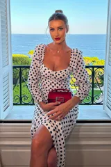 Vestido midi blanco con lunares negros, escote cuadrado, mangas largas abullonadas y corte ajustado.