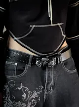 Cinturón de cuero sintético negro con tachas metálicas pequeñas y hebilla decorativa con diseño de tres calaveras.