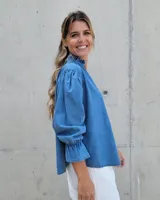 Blusa de algodón con cuello mao y volados, mangas largas con puños elásticos y corte holgado.