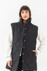 Chaleco largo acolchado color negro, con diseño de rombos, cuello alto y cierre frontal con botones a presión. Cuenta con bolsillos laterales.