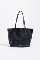 Bolso shopper mediano Bimba y Lola de piel vacuna en color azul oscuro, con textura efecto cocodrilo. Presenta doble asa de hombro, cierre de mosquetón y detalle de logo metálico de la marca en la parte frontal.