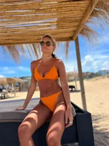 Conjunto de bikini naranja, con corpiño triangular fijo y bombacha vedetina regulable.