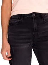 Jeans de denim negro gastado, de corte amplio y tiro medio, con diseño clásico de cinco bolsillos y un sutil roto en la pierna derecha.