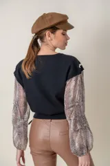 Buzo negro de lana fina con mangas largas abullonadas y laterales de seda con estampado animal print.