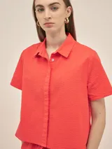 Camisa de manga corta con cuello camisero y botones anacarados, confeccionada en tejido seersucker con estampa floral.