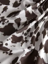 Pollera larga de corte recto confeccionada en tejido mesh con estampado animal print tipo vaca en tonos blanco y marrón oscuro. Presenta cintura elastizada y diseño fluido.
