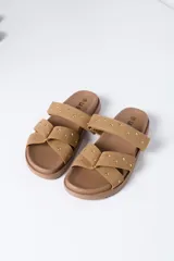 Sandalias planas color beige con dos tiras cruzadas en el empeine decoradas con tachas metálicas, suela ancha y diseño cómodo.