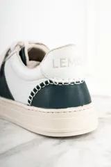 Zapatillas urbanas de cuero blanco con una franja lateral verde oscuro y suela color crema.